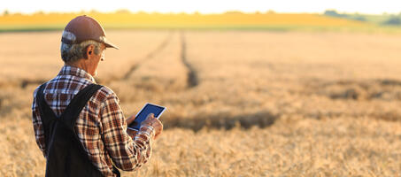 Farmer on tablet in front of field 