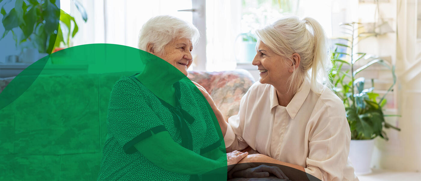 Elderly women comfort one another in a sunny room on a couch